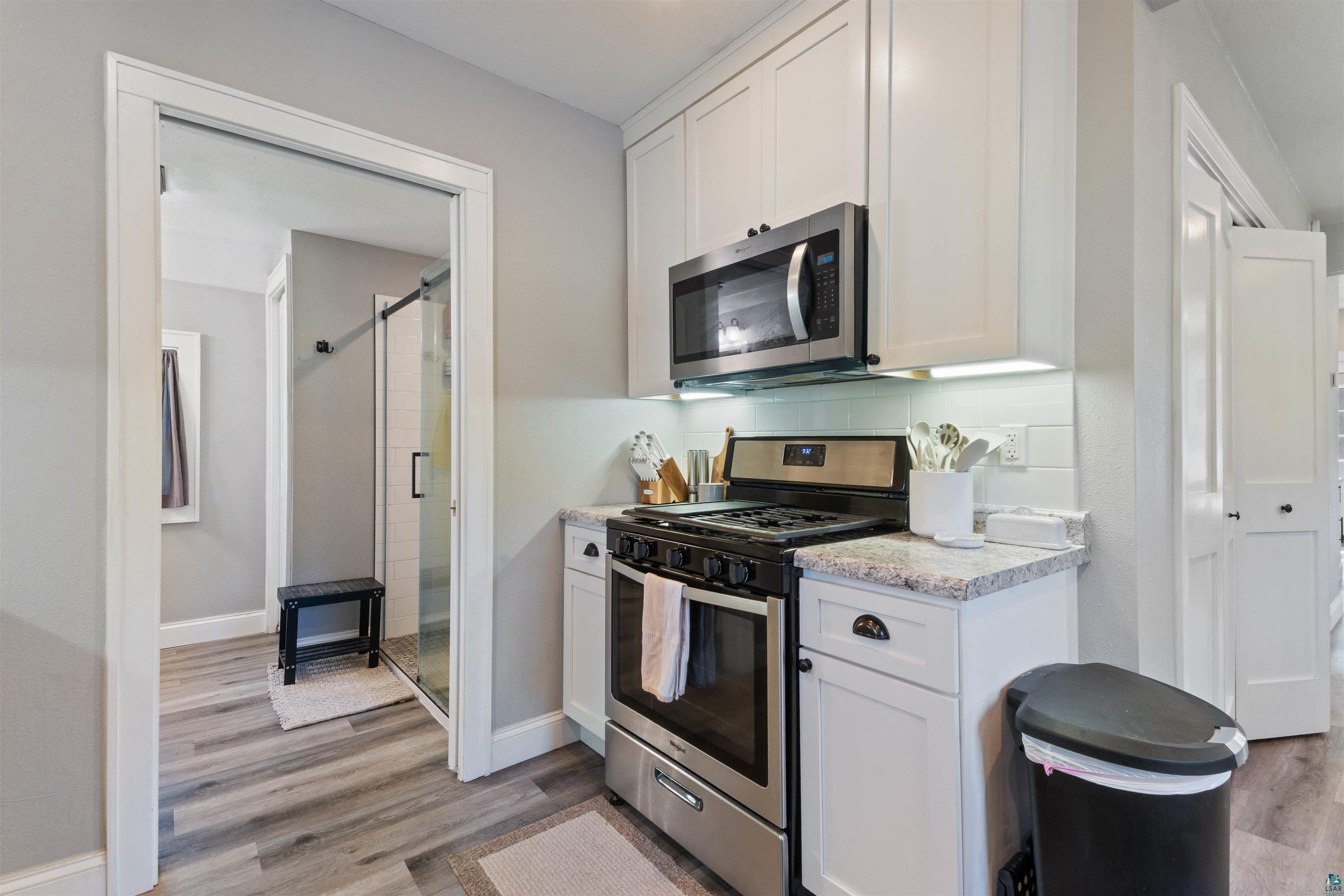 3835 South County Rd K South Range, WI 54874 - Photo 8 of 29 Kitchenette featuring white cabinetry with dark hardware, stainless steel appliances, a white subway tile backsplash, and light-toned granite-look countertops
