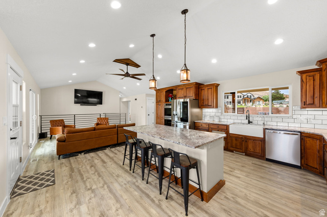 2591 East Washington Dam Road Washington, UT 84780 - Photo 12 of 67 Spacious kitchen featuring an expansive island with seating, stainless steel appliances, a farmhouse sink, subway tile backsplash, and wood-finish flooring