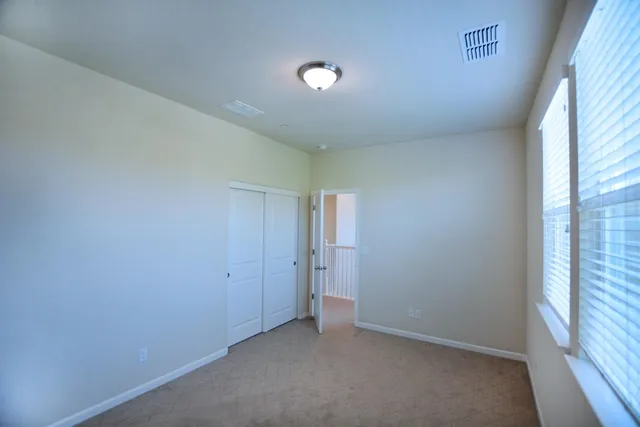 an empty room with a window and a kitchen view