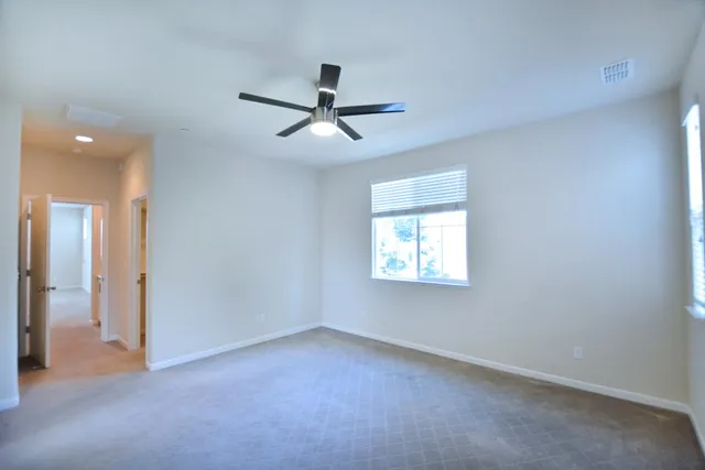 an empty room with a window and a ceiling fan