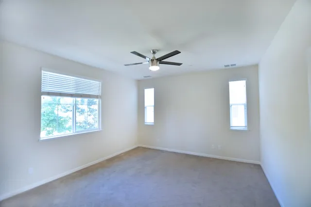 an empty room with windows and a ceiling fan