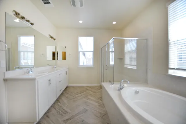 a spacious bathroom with a double vanity sink a mirror and a bathtub