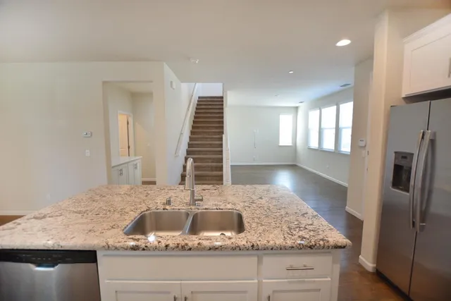 a kitchen with kitchen island granite countertop a sink and a refrigerator