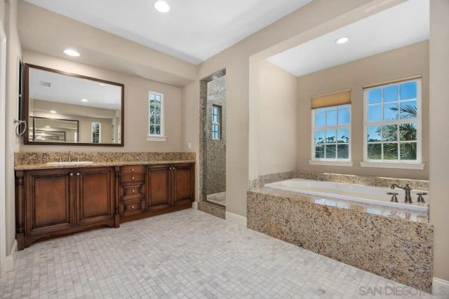 a spacious bathroom with a granite countertop double vanity sink and a large mirror