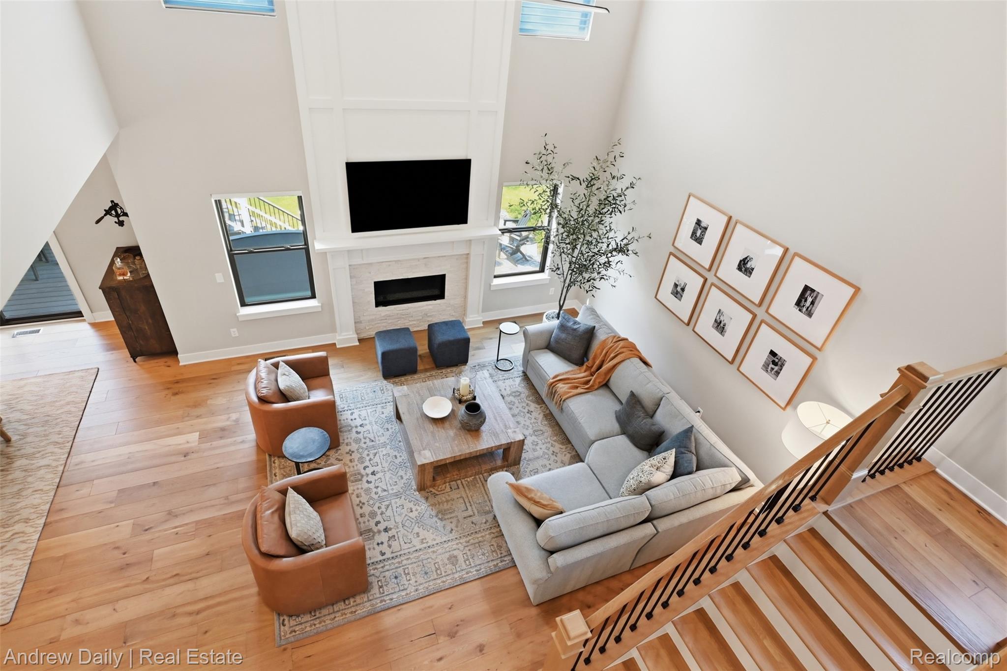 4661 Spears Road Pinckney, MI 48169 - Photo 17 of 56 Soaring ceilings above a living room featuring wood-finish flooring, a fireplace with a stone surround, and large windows
