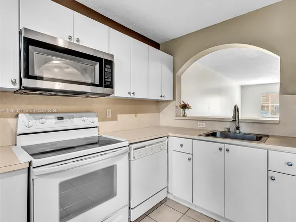 a view of an empty room with a window and a kitchen