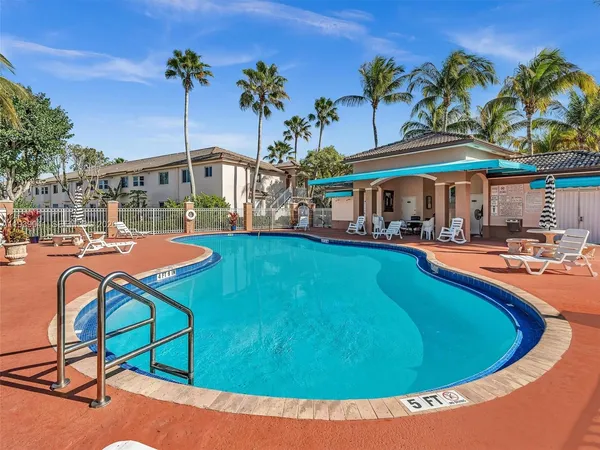 a view of a swimming pool with a lawn chairs and palm trees