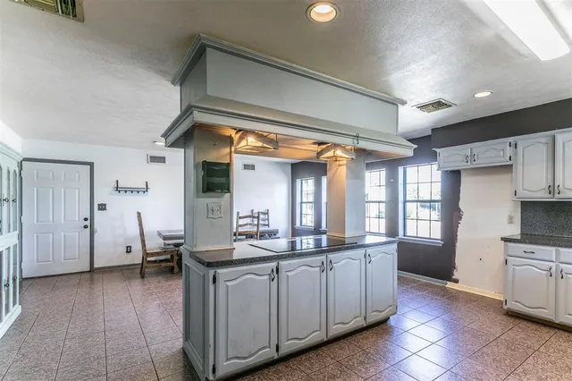 a dining hall with stainless steel appliances kitchen island granite countertop a sink and cabinets