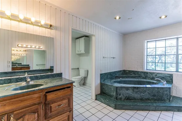 a bathroom with a granite countertop sink and a bathtub