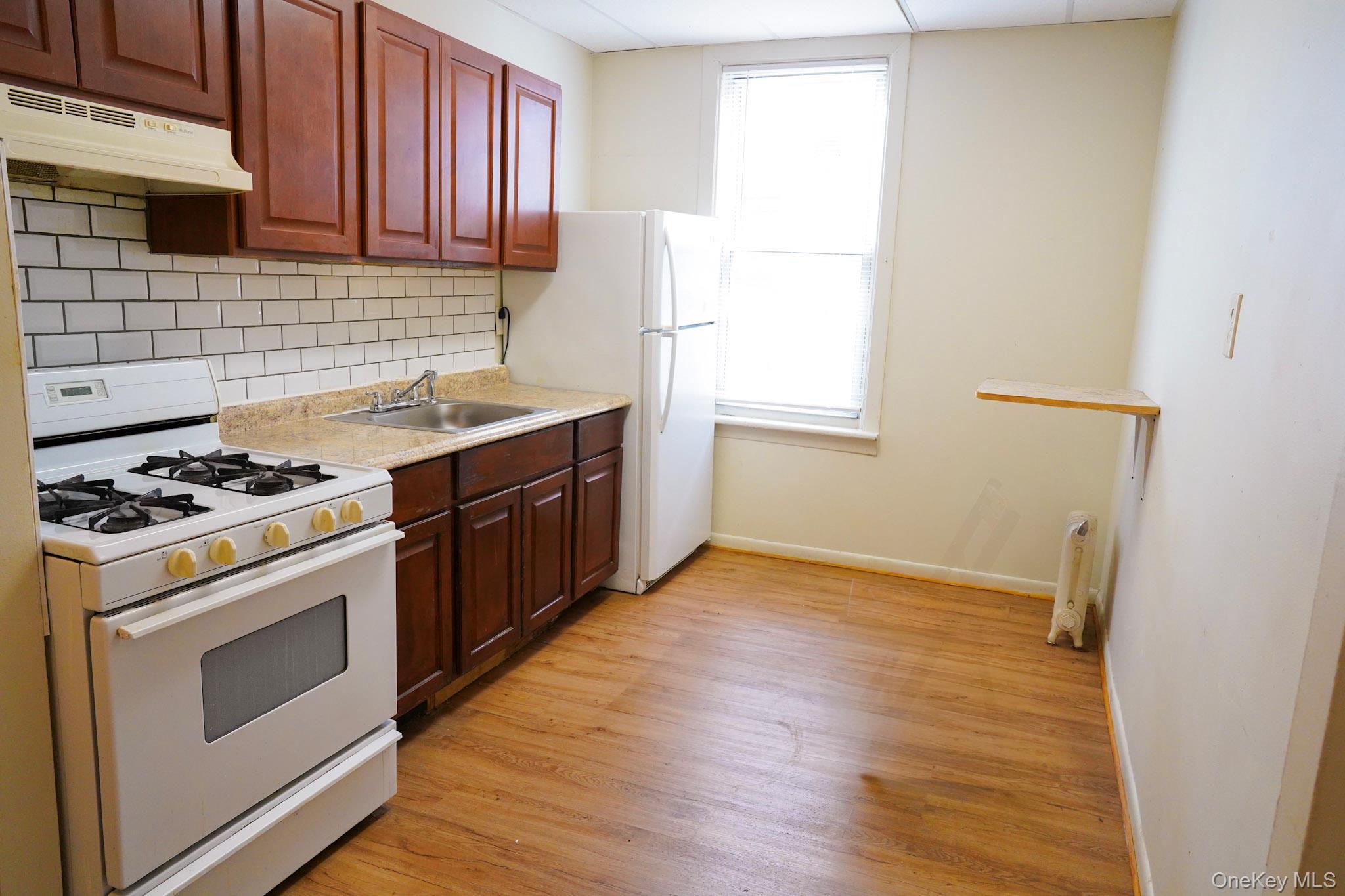80-33 90th Road Queens, NY 11421 - Photo 11 of 20 a kitchen with a stove a sink and a refrigerator