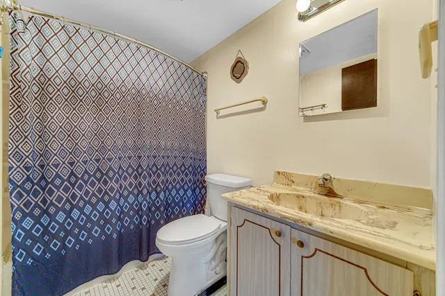 a bathroom with a granite countertop toilet sink and mirror