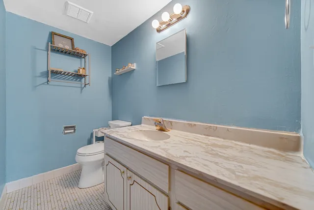 a bathroom with a granite countertop toilet sink and mirror