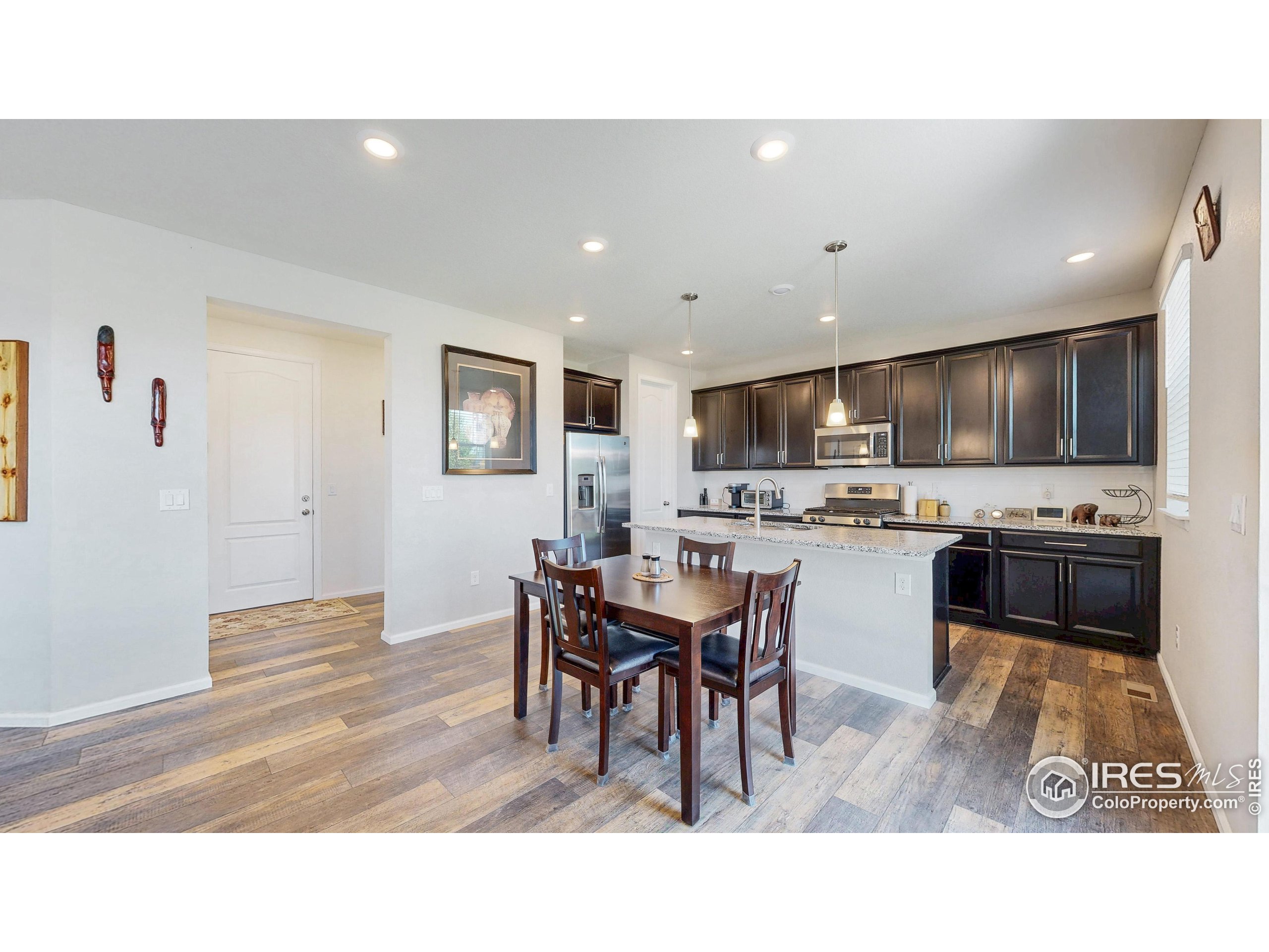 4861 St Vrain Road Firestone, CO 80504 - Photo 10 of 43 a living room with stainless steel appliances kitchen island granite countertop a dining table chairs and a refrigerator