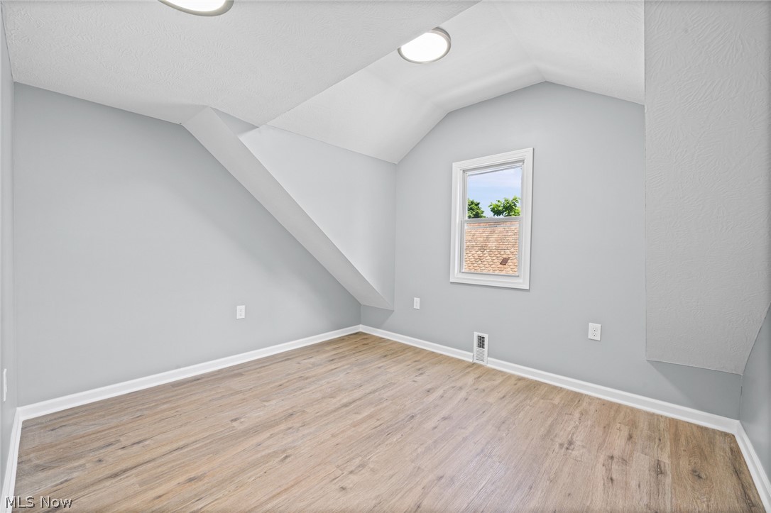 3925 Riverside Avenue Cleveland, OH 44109 - Photo 36 of 48 Attic room featuring sloped ceilings, wood-finish flooring, two recessed ceiling lights, a rectangular window with white trim, and light gray wall paint
