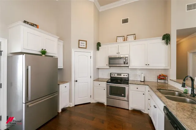 a kitchen with stainless steel appliances granite countertop a refrigerator a sink a stove and white cabinets