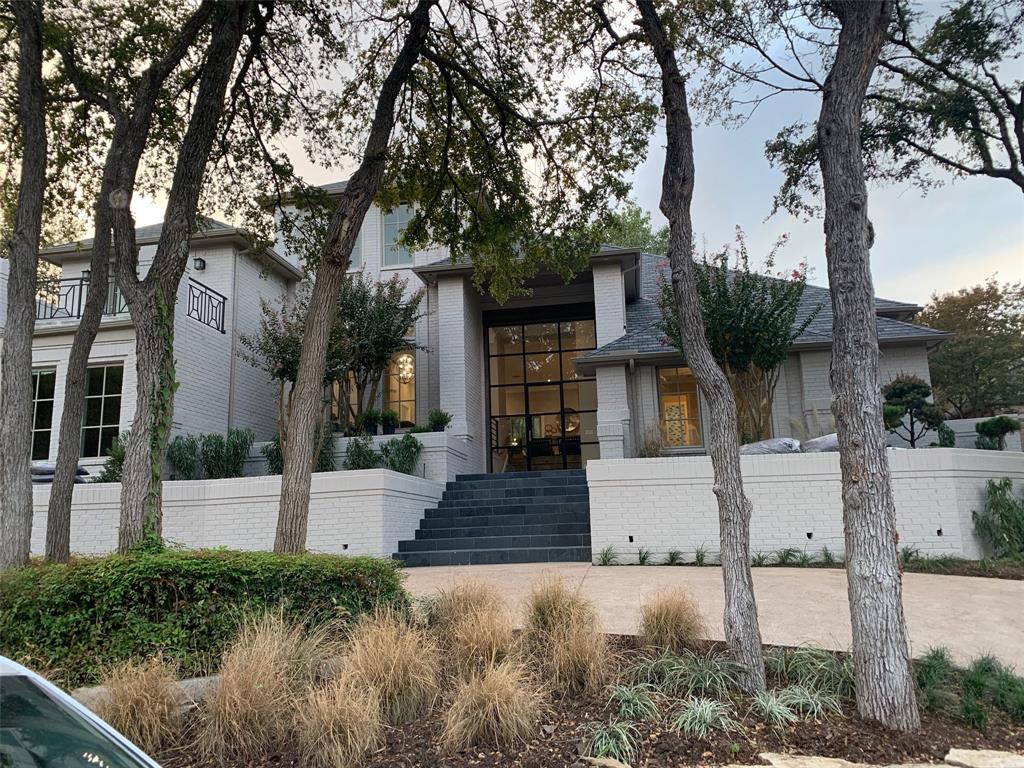 a front view of a house with a yard and tree s