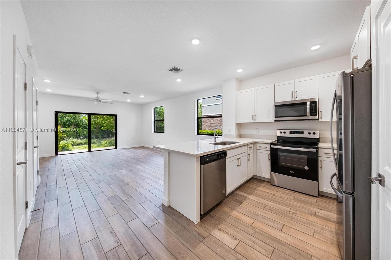 186 Southeast 5th Court, Unit 186 Deerfield Beach, FL 33441 - Photo 3 of 10 a white kitchen with wooden floor and stainless steel appliances