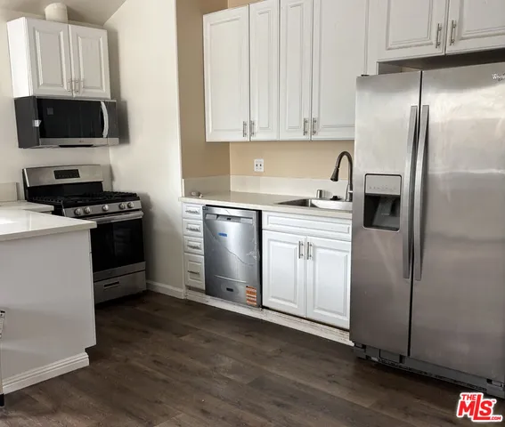 a kitchen with granite countertop a refrigerator stove and sink