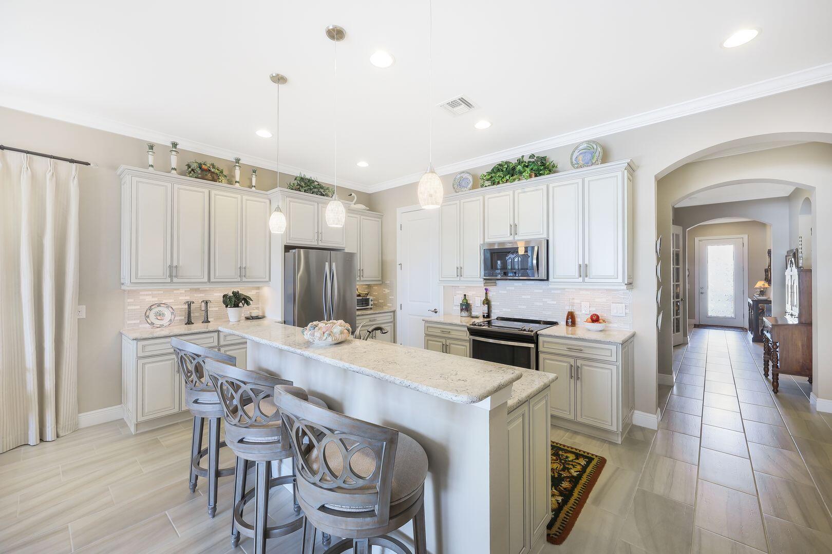 1433 Redona Way Naples, FL 34113 - Photo 9 of 50 a kitchen with kitchen island a stove a table and chairs in it