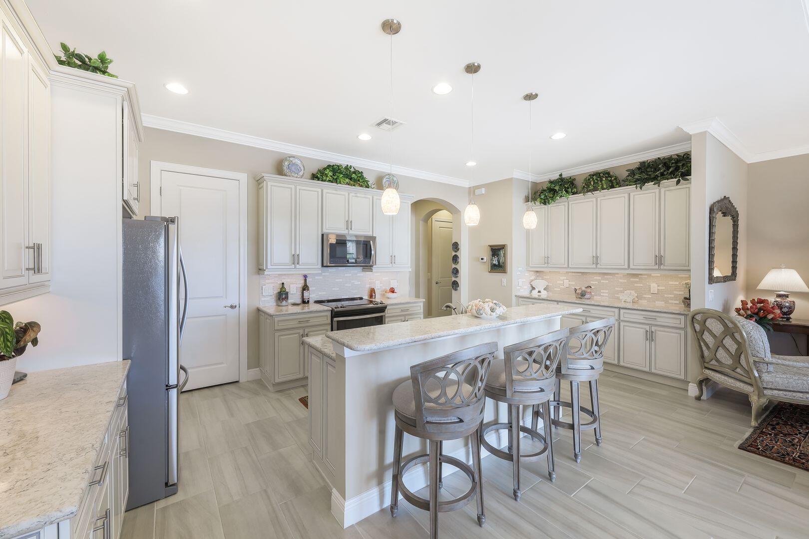1433 Redona Way Naples, FL 34113 - Photo 10 of 50 a kitchen with stainless steel appliances a dining table chairs refrigerator and sink
