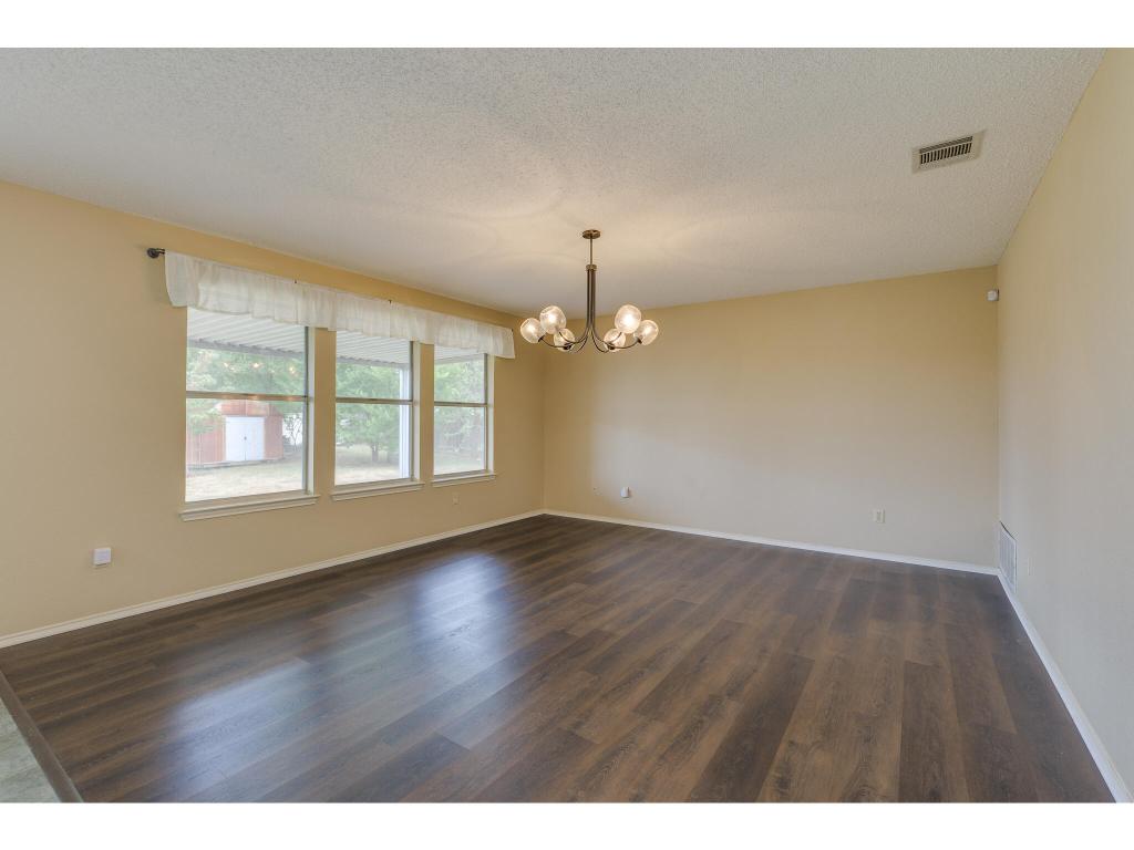 3912 Lemos Drive Austin, TX 78728 - Photo 16 of 40 an empty room with wooden floor chandelier and windows