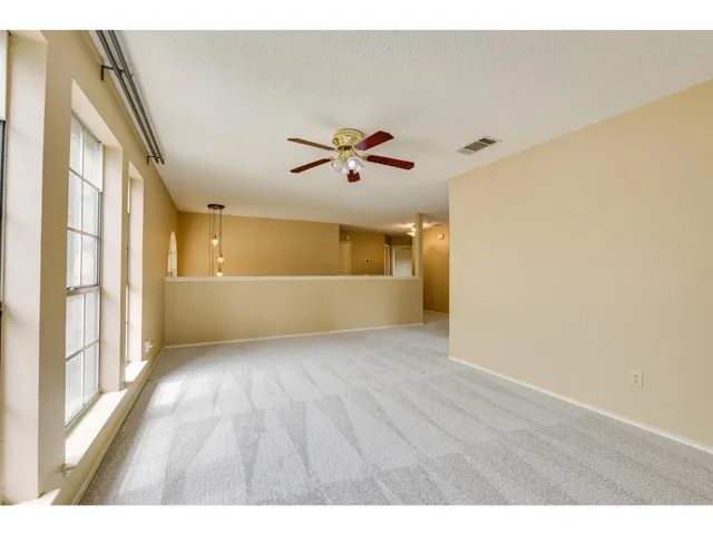 a view of an empty room with a window and kitchen view