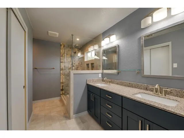 a bathroom with a granite countertop sink mirror and a shower