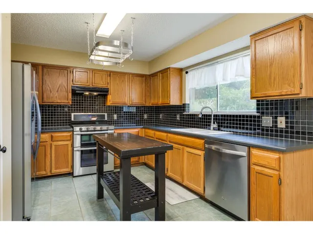 a kitchen with stainless steel appliances a sink window and cabinets
