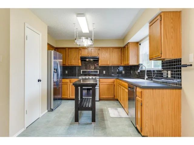 a kitchen with granite countertop a stove a sink and a refrigerator