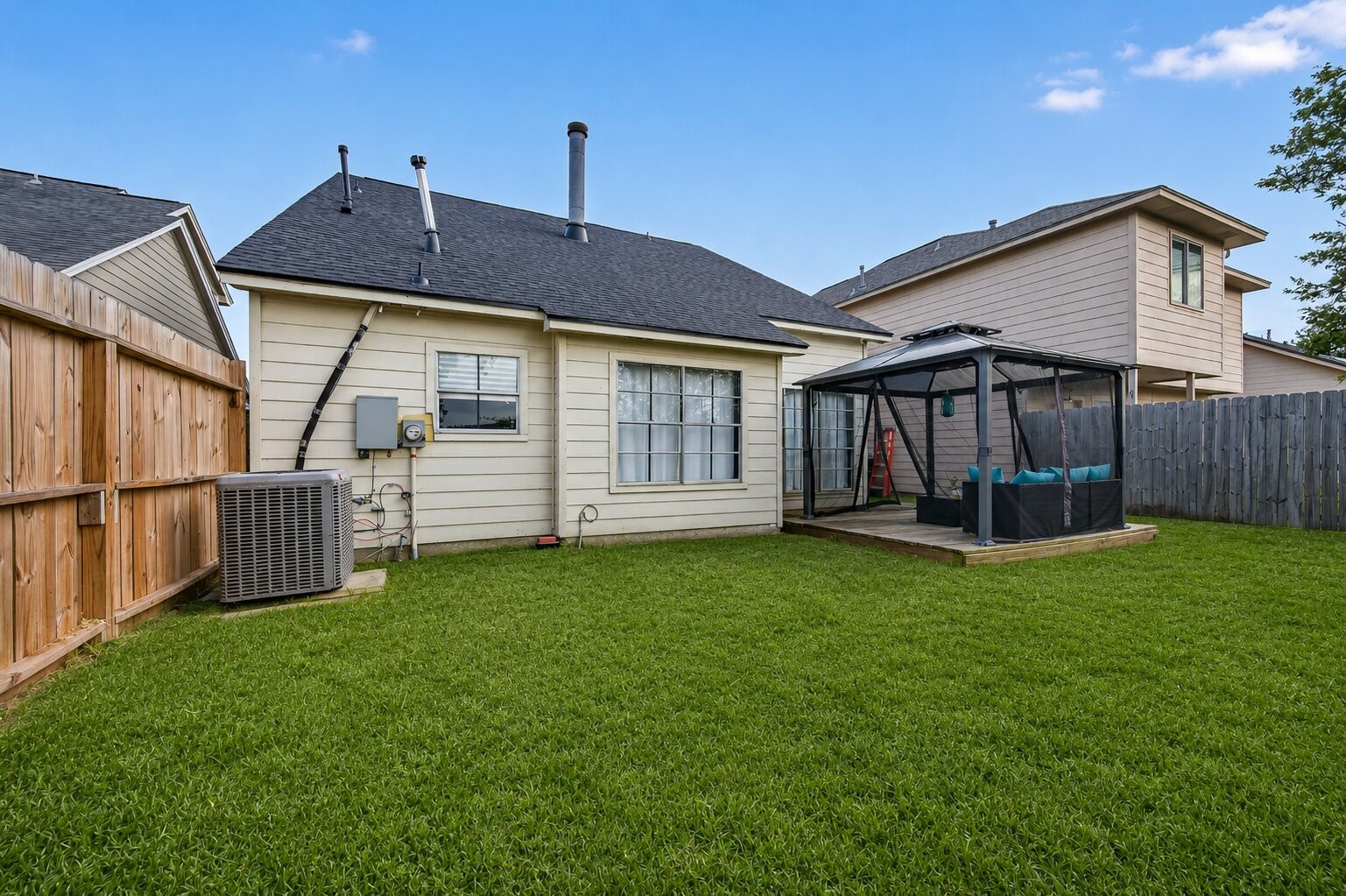 18446 North Willow Bluff Road Katy, TX 77449 - Photo 31 of 33 This backyard features a well-maintained lawn, a cozy patio with a gazebo, and a wooden privacy fence, providing a perfect space for outdoor relaxation and entertainment.