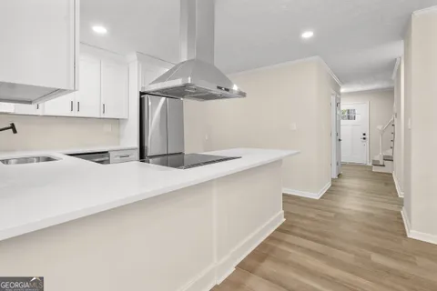 a kitchen with stainless steel appliances a refrigerator a sink dishwasher a stove and white cabinets with wooden floor