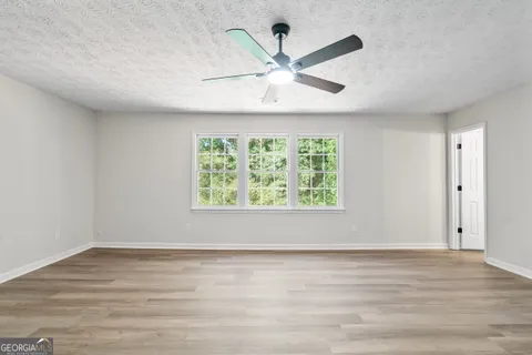 an empty room with wooden floor fan and windows