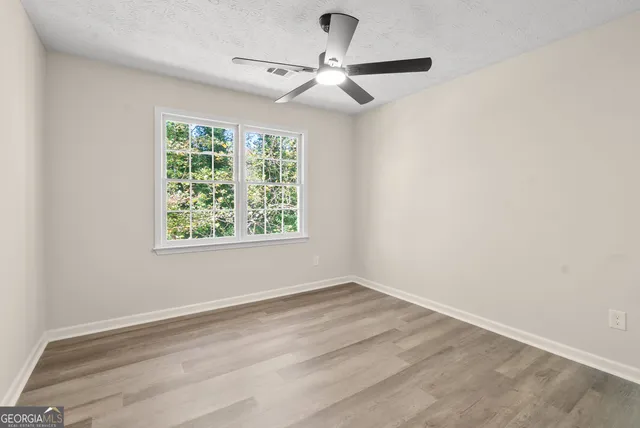an empty room with a window and a fan