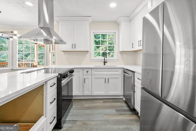 a kitchen with stainless steel appliances a sink cabinets and a window