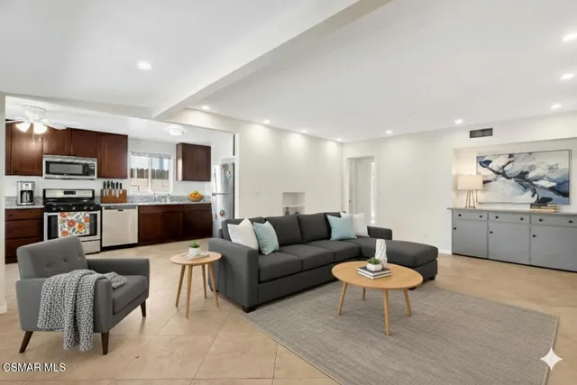 a living room with furniture a kitchen view and a flat screen tv