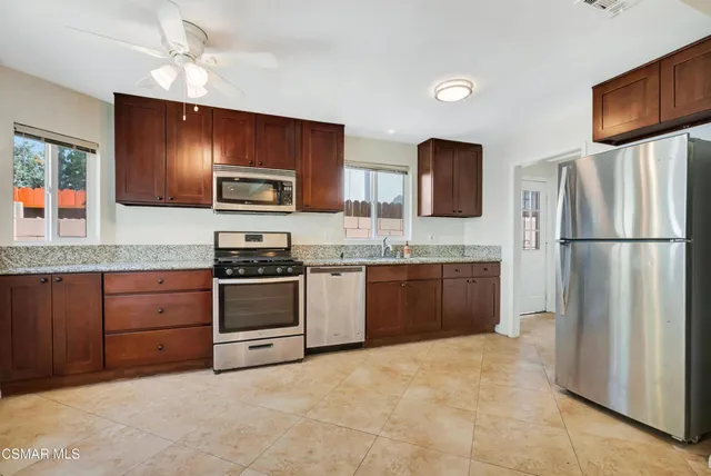 a kitchen with granite countertop a refrigerator stove top oven a sink and dishwasher