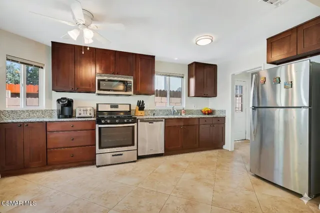 a kitchen with granite countertop a refrigerator stove top oven a sink and dishwasher