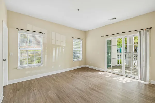 an empty room with wooden floor and windows