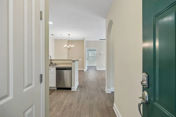 a view of a hallway with wooden floor and a kitchen
