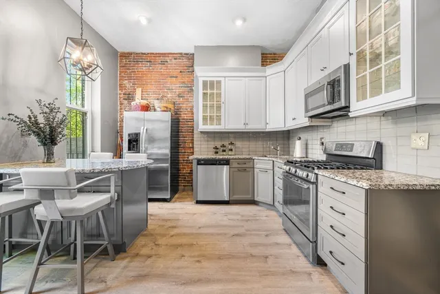 a kitchen with stainless steel appliances granite countertop a stove top oven a sink dishwasher a dining table and chairs with wooden floor