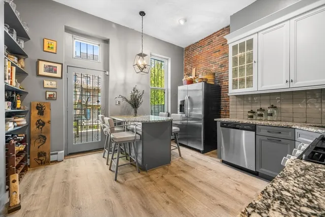 a kitchen with stainless steel appliances granite countertop a refrigerator a stove top oven a sink dishwasher and wooden cabinets with wooden floor