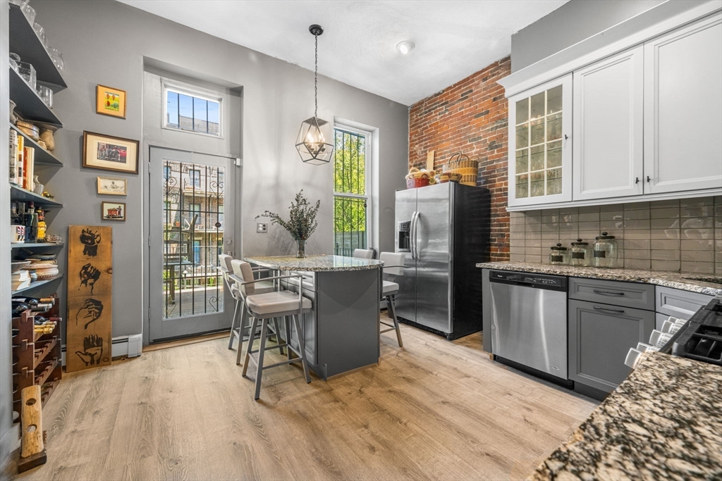 50 East Springfield Street, Unit 1 Boston, MA 02118 - Photo 4 of 23 a kitchen with stainless steel appliances granite countertop a refrigerator a stove top oven a sink dishwasher and wooden cabinets with wooden floor