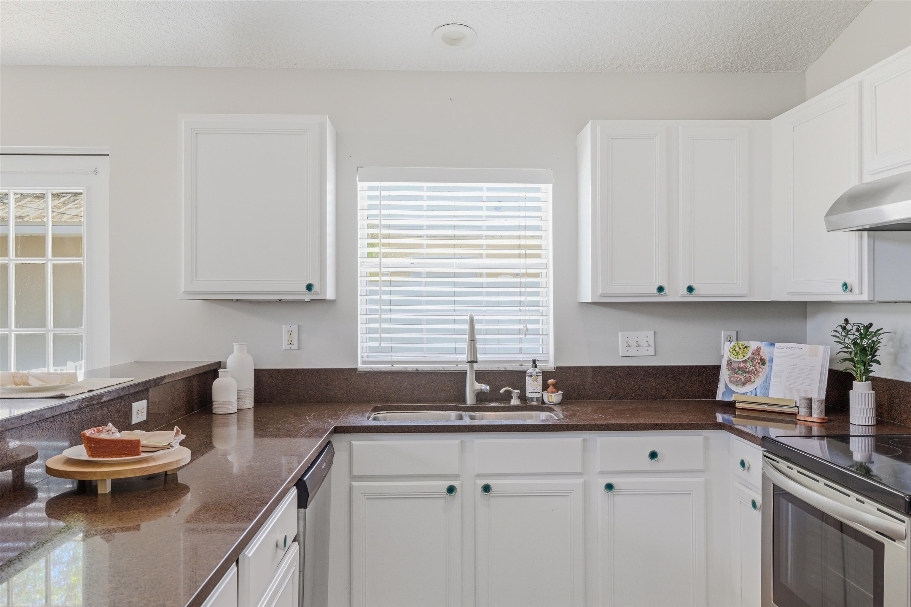 207 11th Street St. Augustine, FL 32080 - Photo 13 of 28 a kitchen with granite countertop a sink stove and cabinets