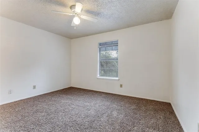 an empty room with a chandelier fan and windows