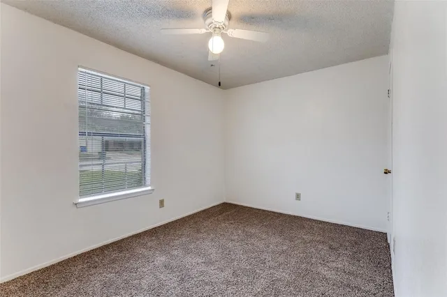 an empty room with a window and a ceiling fan