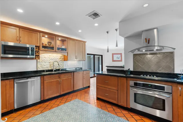 a kitchen with stainless steel appliances granite countertop a refrigerator a sink and a stove