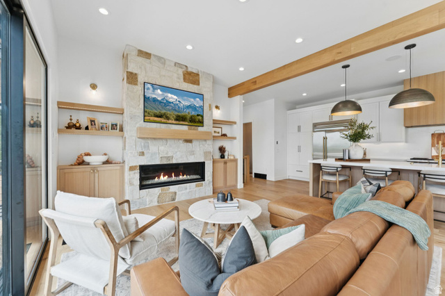1400 Weber Wild Road Oakley, UT 84055 - Photo 17 of 55 Open-concept living area featuring a stone-clad fireplace with a linear firebox, natural wood-finish mantel, and integrated built-in cabinetry with open shelving