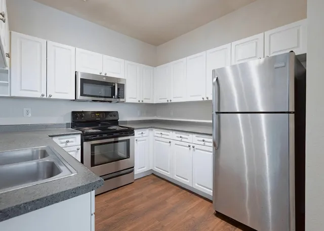 a kitchen with cabinets stainless steel appliances and wooden floor