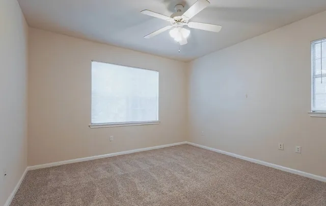 an empty room with a window and a fan