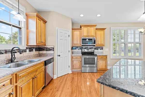 a kitchen with stainless steel appliances granite countertop a stove a sink and a microwave